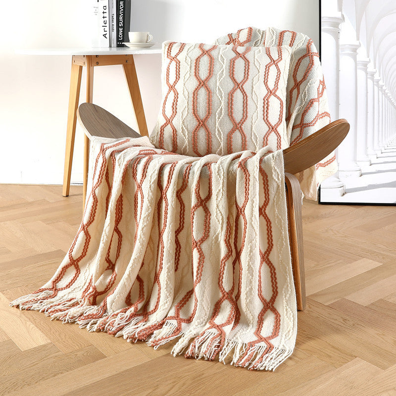 Beige sofa throw blanket with orange and white diamond knit pattern and fringe tassels