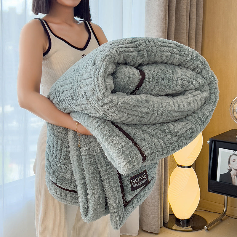 Plush velvet winter blanket in cool gray with dark striped trim and stitched logo label
