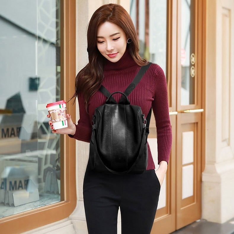 Black PU leather backpack with top handle and dual shoulder straps, front zipper pocket