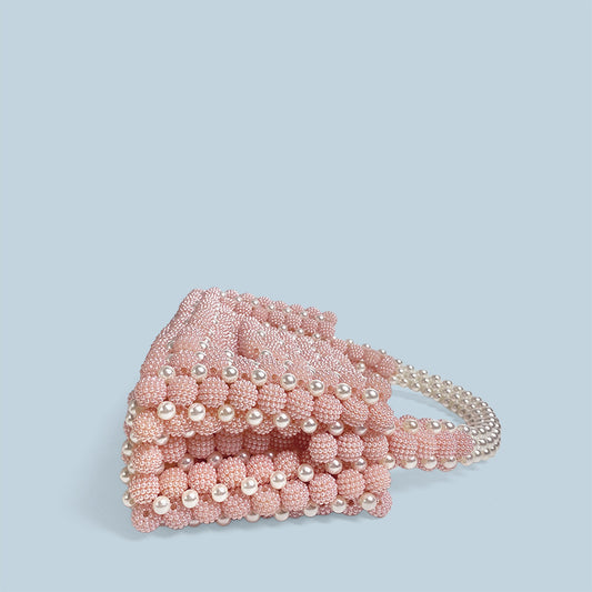 Pink beaded handbag on a light blue background