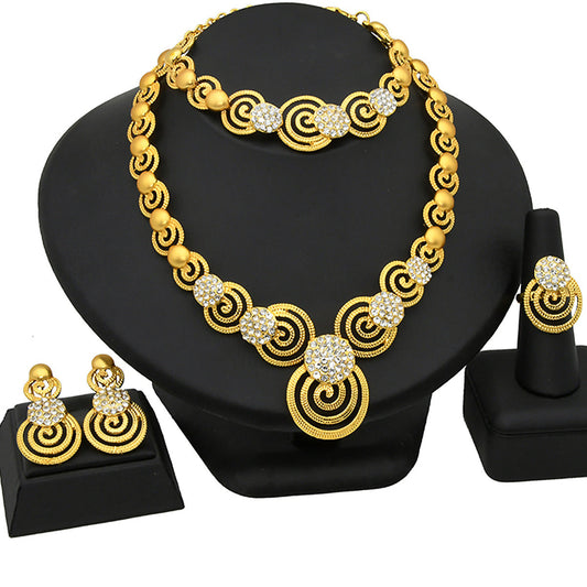 Gold necklace with circular design and matching earrings on a black stand.