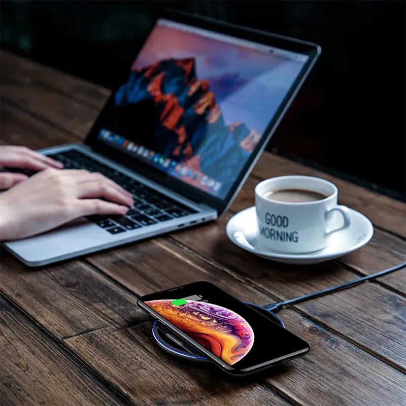 Black wireless phone charger with a smartphone placed on the charging surface