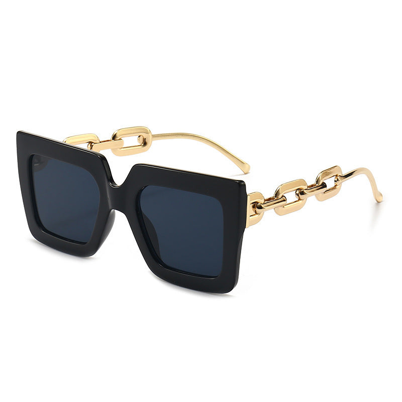 Square chain sunglasses with black frame and dark lenses, gold chain bridge detail.