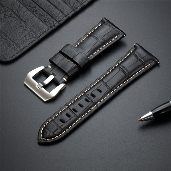 Black leather watch strap with metal buckle and tan edge stitching.