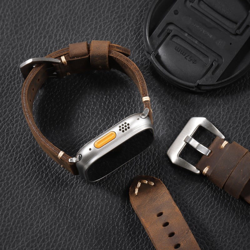 Brown leather watch strap with stitched edge and metal buckle; shown with watch case