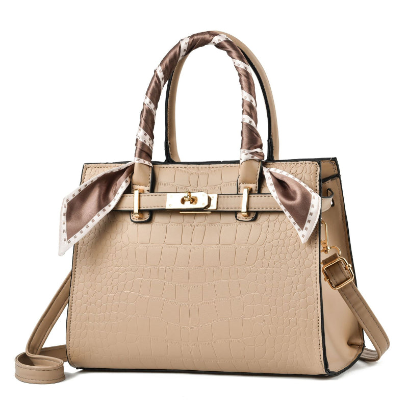 Beige croc-textured tote bag with brown patterned scarf handles and shoulder strap