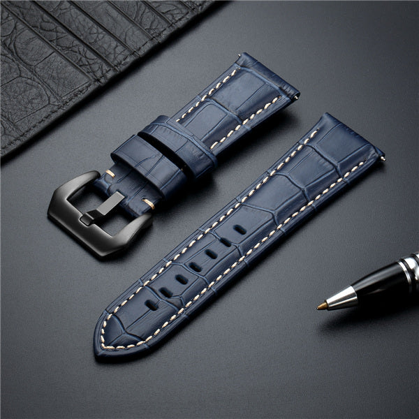 Blue leather watch strap with metal buckle and cream contrast stitching.