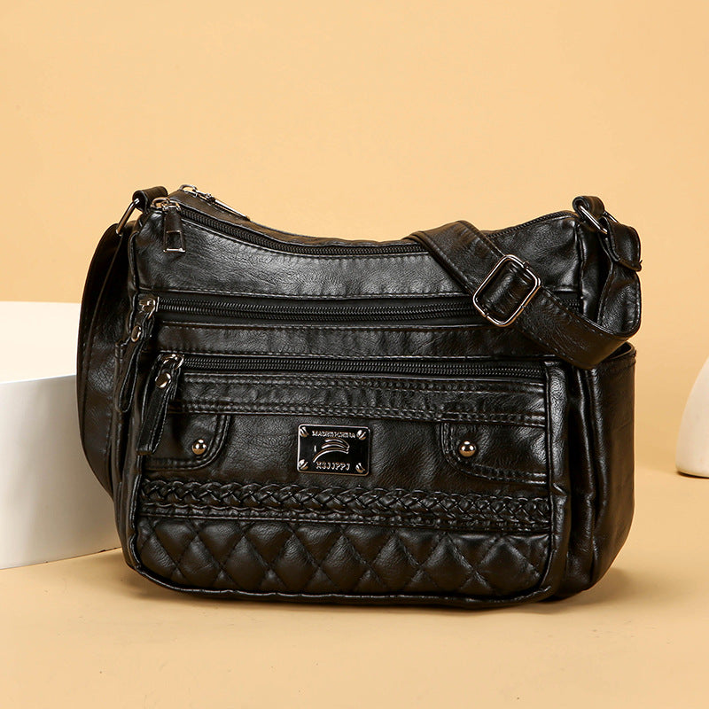 Black soft leather shoulder bag with quilted braided front, multiple zip pockets, and strap
