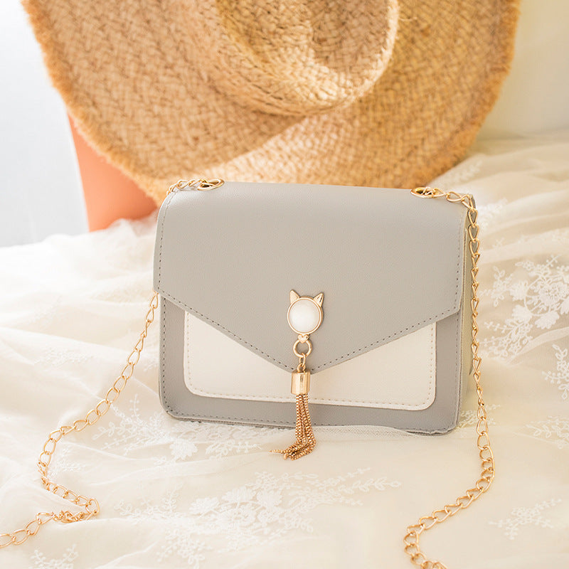 Small square PU leather crossbody bag with flap, tassel chain, light gray and white panels.