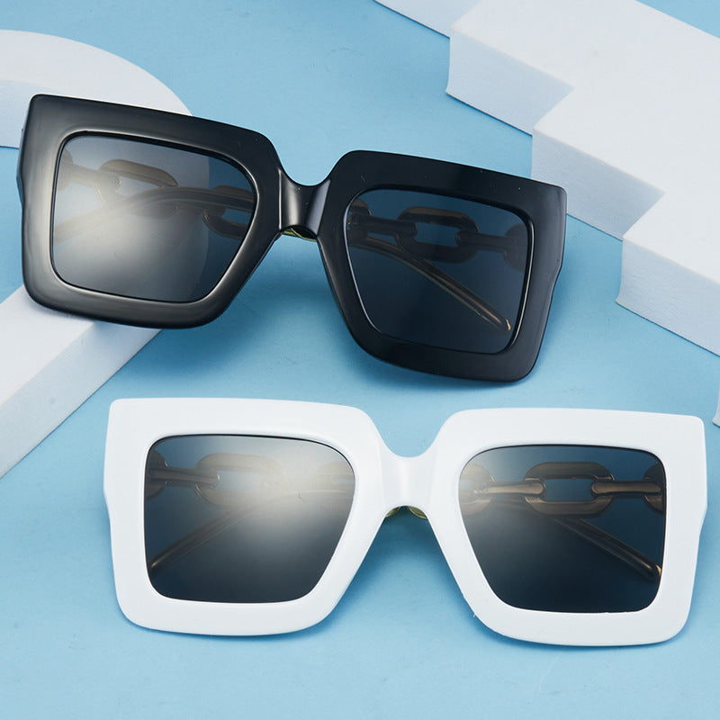Square chain sunglasses: black and white frames with dark lenses and gold hardware.