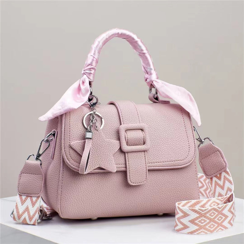 Pink handbag with top flap, front buckle detail, and patterned chevron side straps