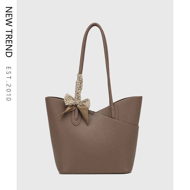 Brown textured shoulder handbag with bow and dangling charm detail