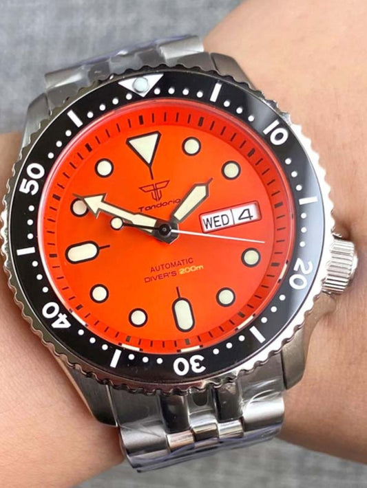 Wrist wearing a watch with an orange dial and silver case.