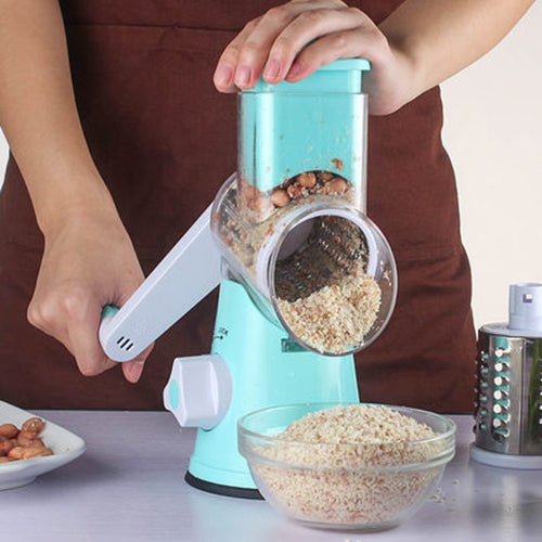 Teal manual rotary slicer filling the drum with ingredients, held by hands