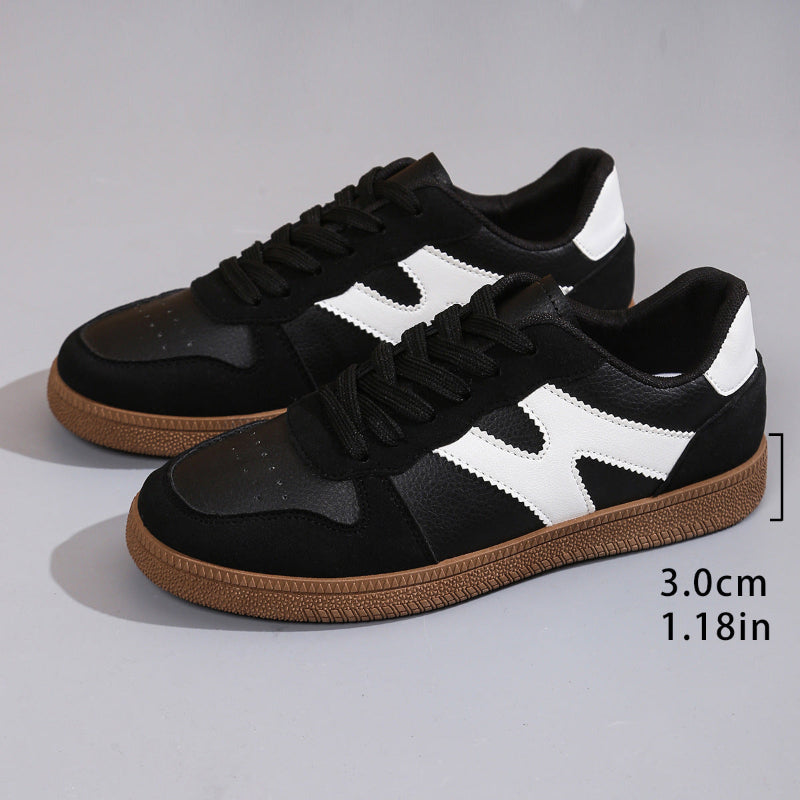 Women's low-top color-block sneakers, black with white panels, lace-up style and gum outsole.