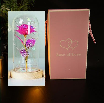 Glass dome with pink and purple flowers and a 'Rose of Love' box on a dark background