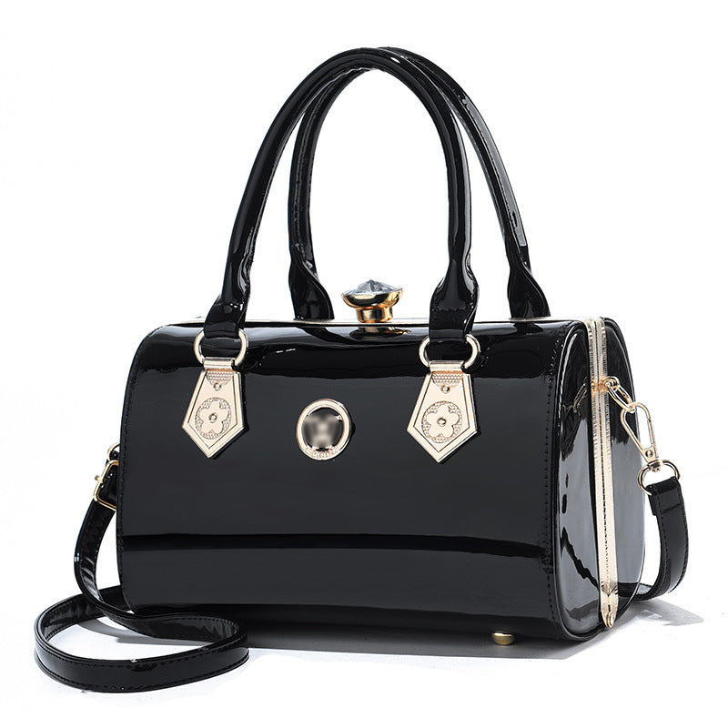 Black glossy PU handbag with top handles, gold clasp, front ring detail, and crossbody strap