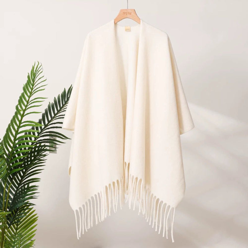 Off-white tassel-fringe travel cape with draped fit and relaxed poncho sleeves