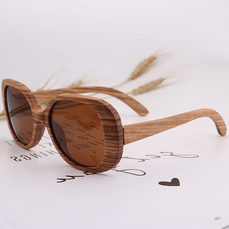 Brown wood-framed sunglasses with amber-brown oval lenses and curved arms