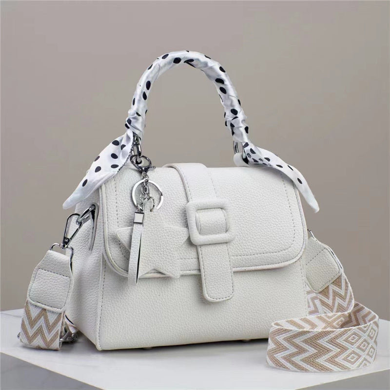 White handbag with top flap, front buckle detail, and black polka-dot handle scarf