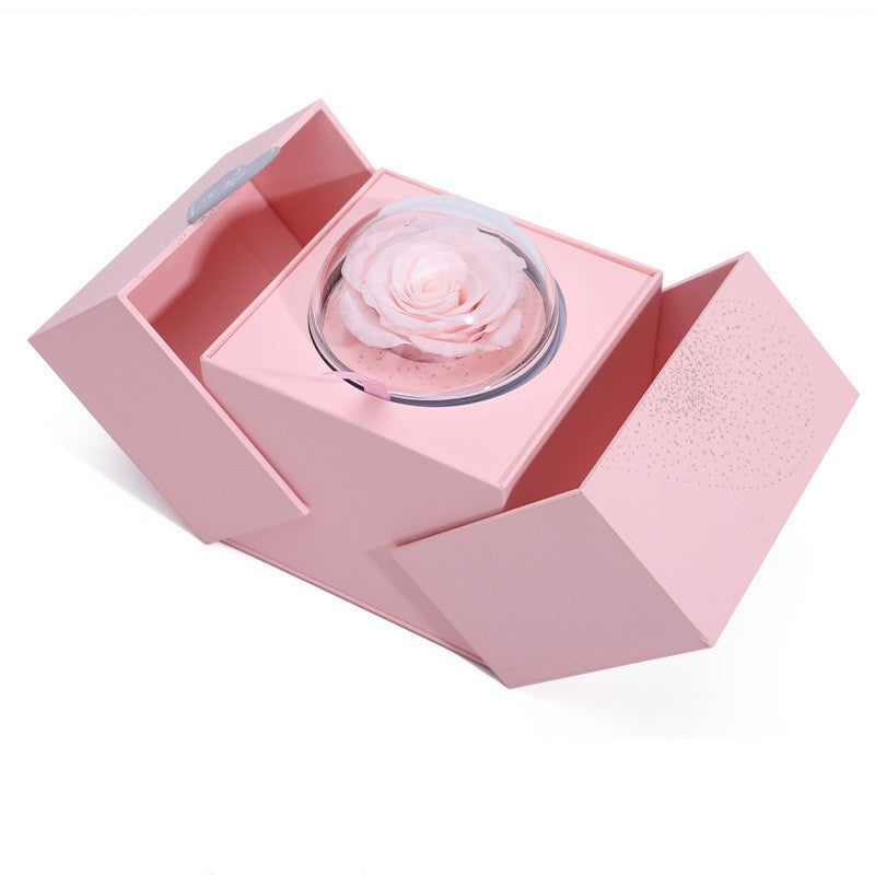 Pink gift box open with clear glass dome containing a light pink rose