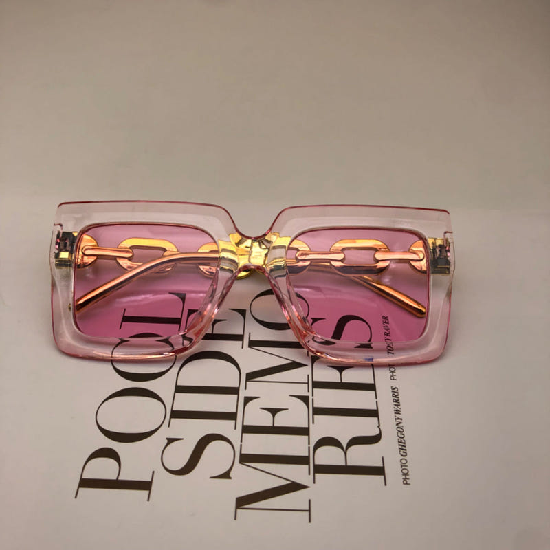 Square pink sunglasses with gold chain detail and pink-tinted lenses, front view