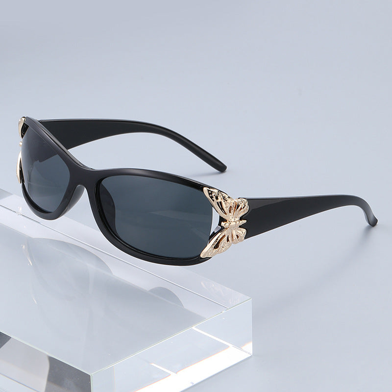 Black driving sunglasses with dark lenses and gold-tone emblem detail at the center
