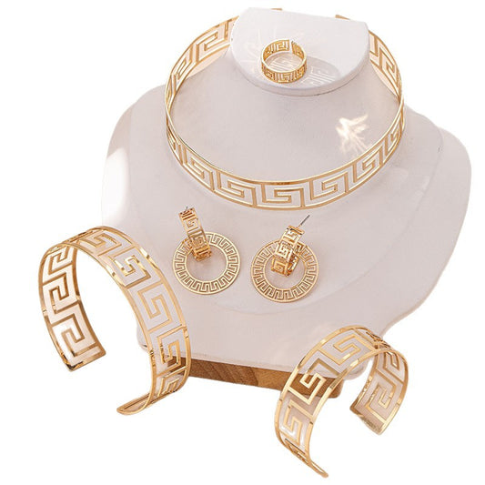 Gold jewelry set including bracelet, ring, and earrings on a white stand with a white background