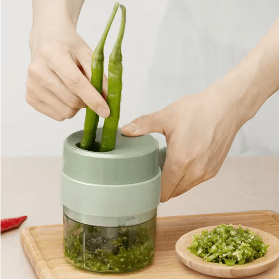 Mini food chopper with transparent base, chopping green vegetables with hands