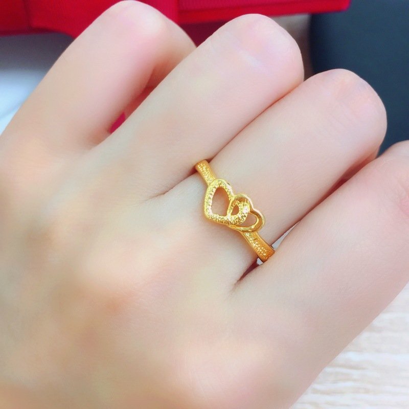 Gold-plated heart ring worn on a finger, with an openwork heart design