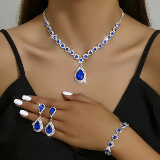 Jewelry set with necklace, earrings, and bracelet featuring blue gemstones on a model.