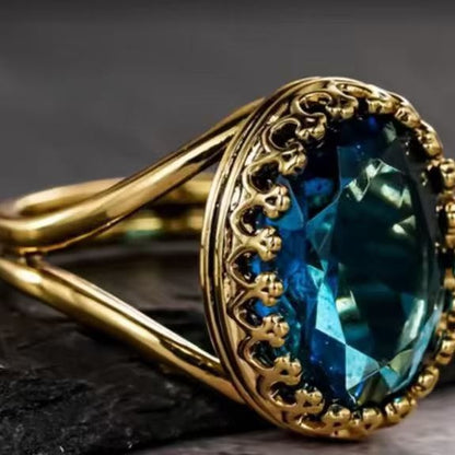 Teal-blue oval gemstone ring in gold with detailed filigree bezel and sleek band