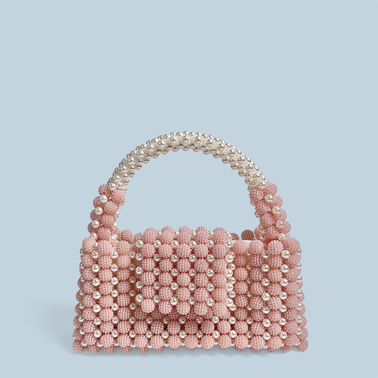 Pink beaded handbag with pearl handle on a light blue background
