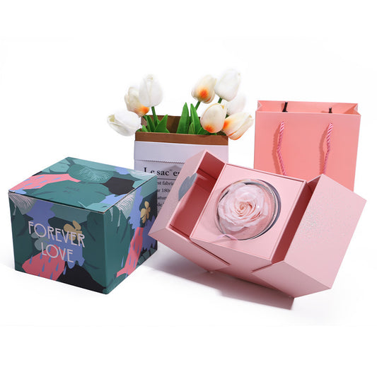 Pink box with a rose inside, surrounded by decorative items on a white background