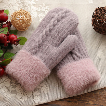 Pair of gray and pink fuzzy gloves on a decorative surface with pomegranates and spherical decorations.
