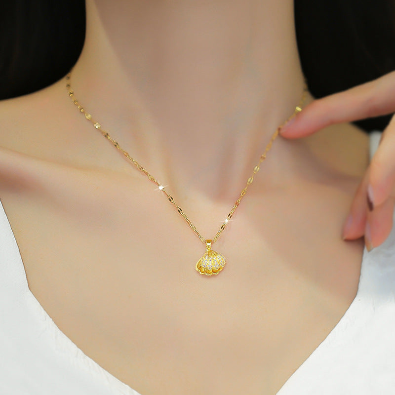 Gold tone chain necklace with small seashell pendant and round pearl centerpiece