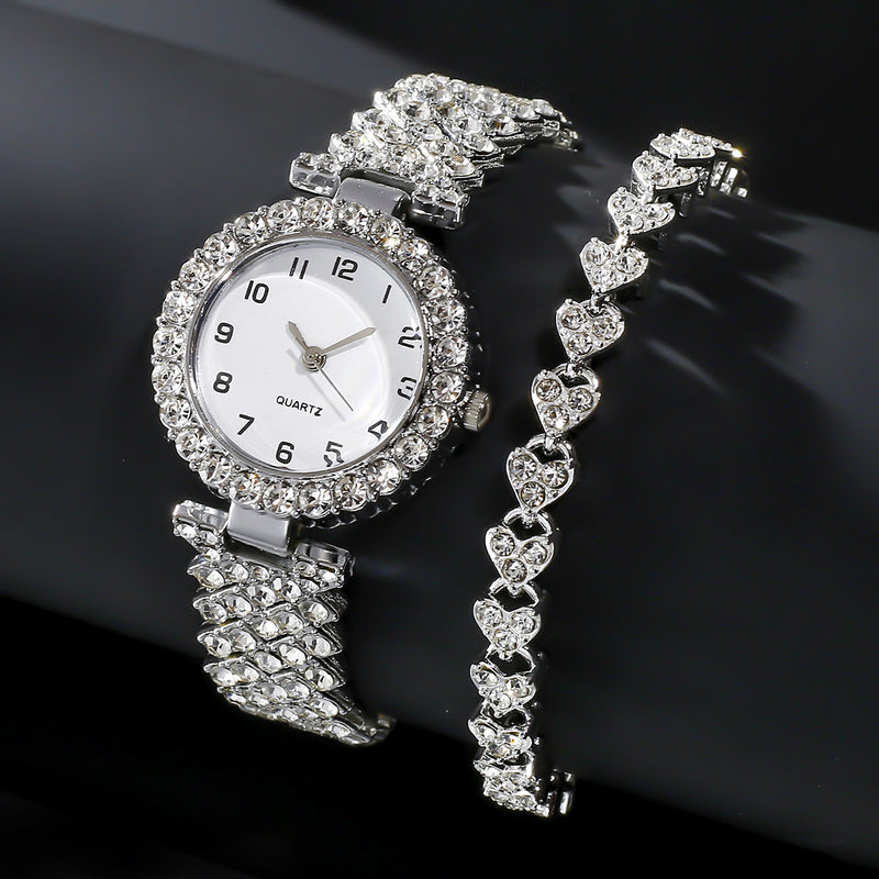 Silver-tone watch and matching stone-set heart-link bracelet on a dark background
