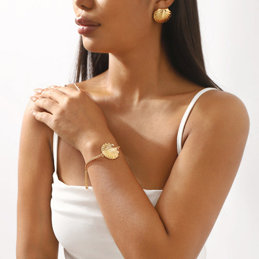 Woman wearing gold bracelet and earrings on a white background