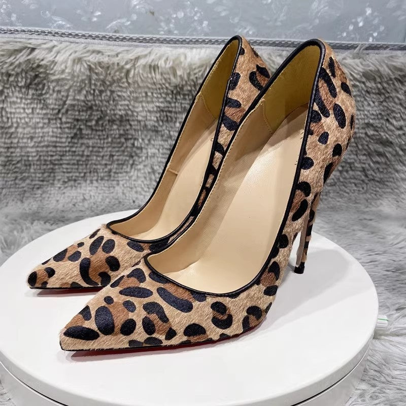 Leopard print high-heeled shoes on a white platform with a gray textured background