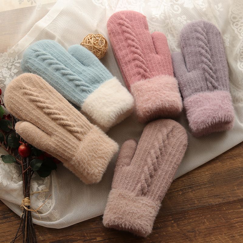 Set of colorful knitted mittens on a textured surface with a wooden background