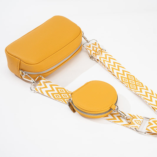 Yellow crossbody bag with a strap featuring a white and yellow pattern on a white background