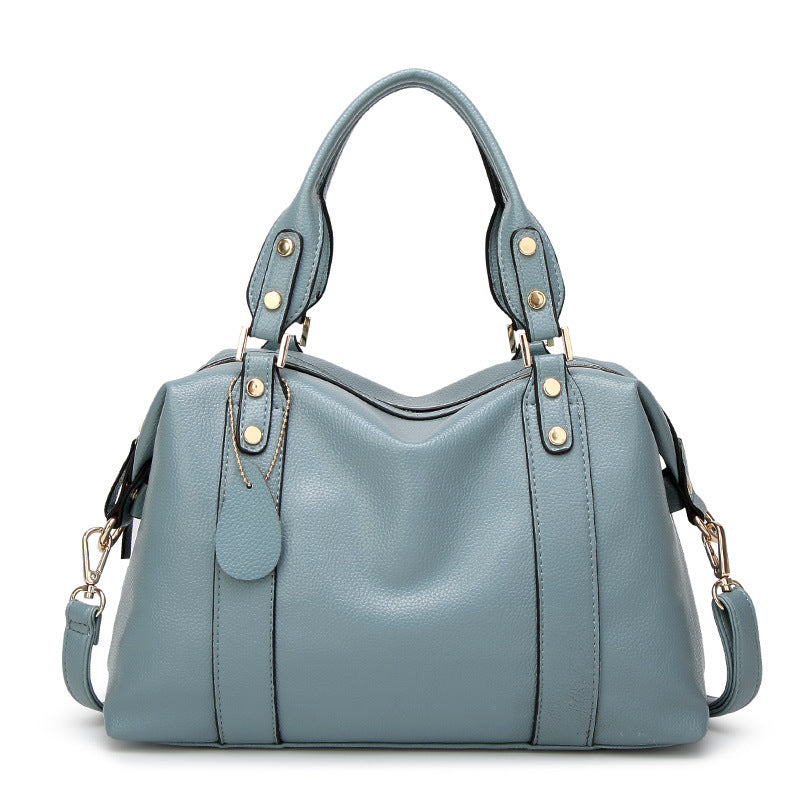 Blue PU leather tote handbag with top handles, front seam detail, and gold stud accents