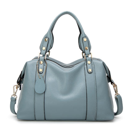 Blue PU leather tote handbag with top handles, front seam detail, and gold stud accents