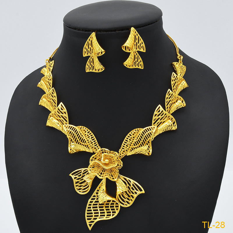 Gold necklace and earrings set on a black mannequin with a light gray background