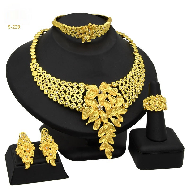 Gold jewelry set including necklace, earrings, and ring on a black stand.