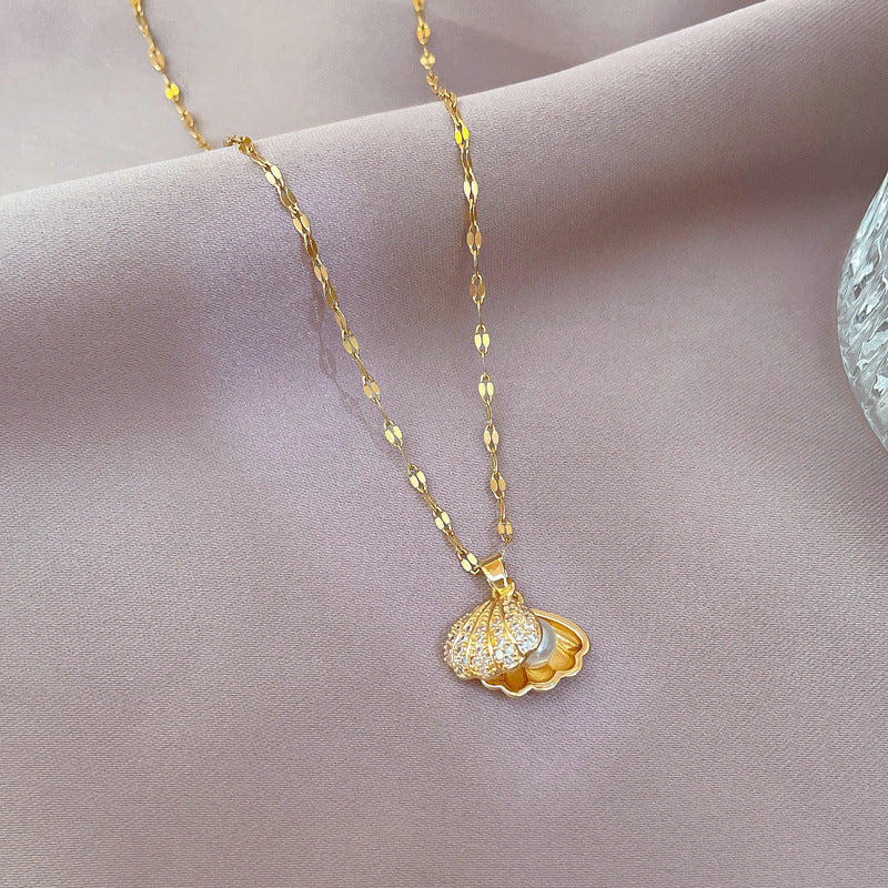 Gold tone pendant necklace with textured scallop seashell charm and round pearl