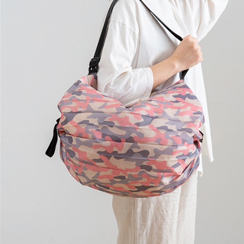 Person holding a pink and purple camouflage bag against a white background
