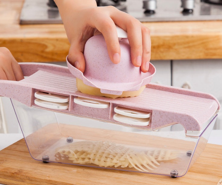 Person using a kitchen tool to slice potatoes on a wooden countertop.