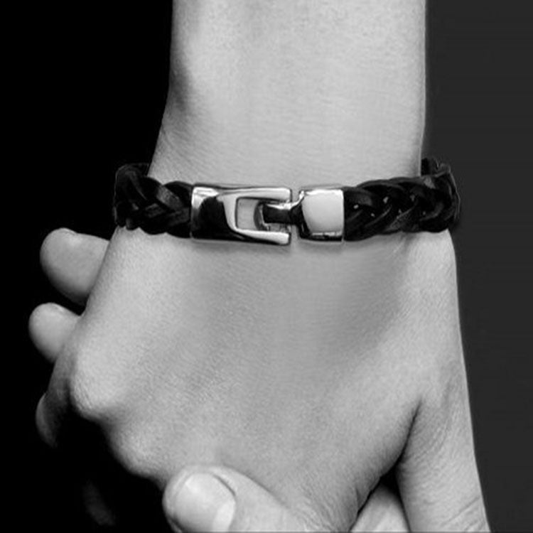 Black braided leather bracelet with silver-tone buckle clasp on wrist.