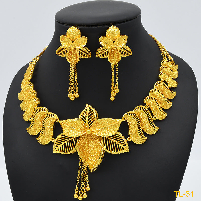 Gold necklace and earrings set on a black mannequin with a gray background